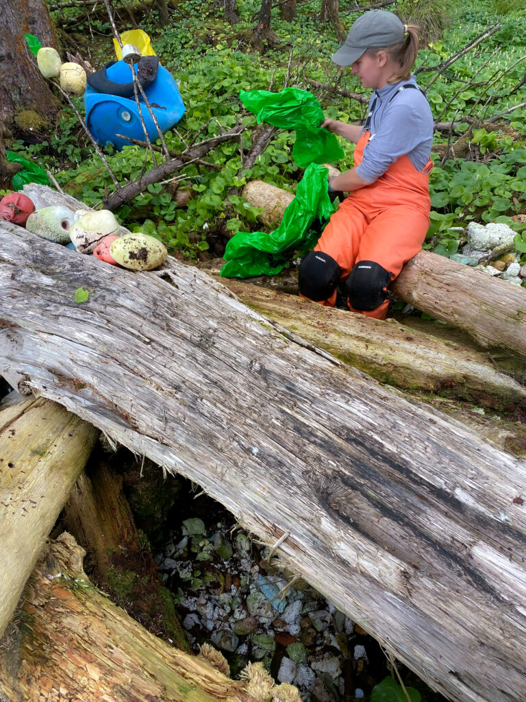 person pulling trash bags while sitting on a log