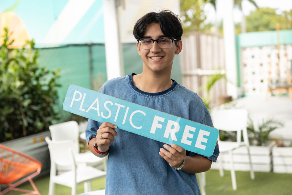 Student holds up Plastic Free Cities sign